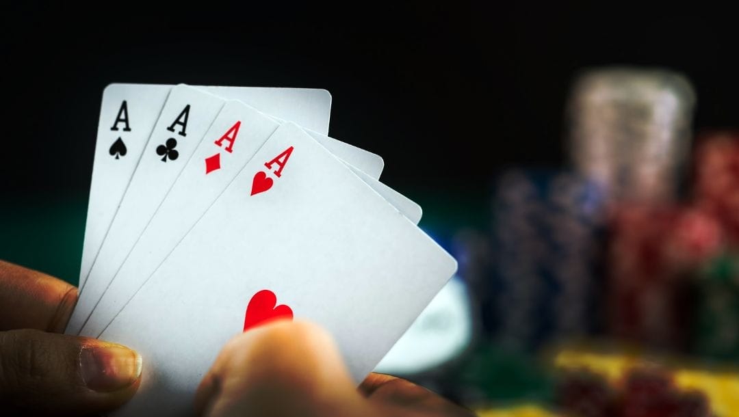 four of a kind ace playing cards with stacks of poker chips blurred in the background