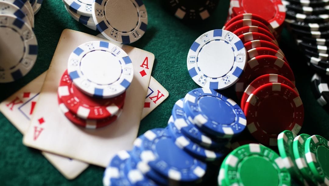 an ace and king of diamonds between piles of poker chips on a green felt poker table