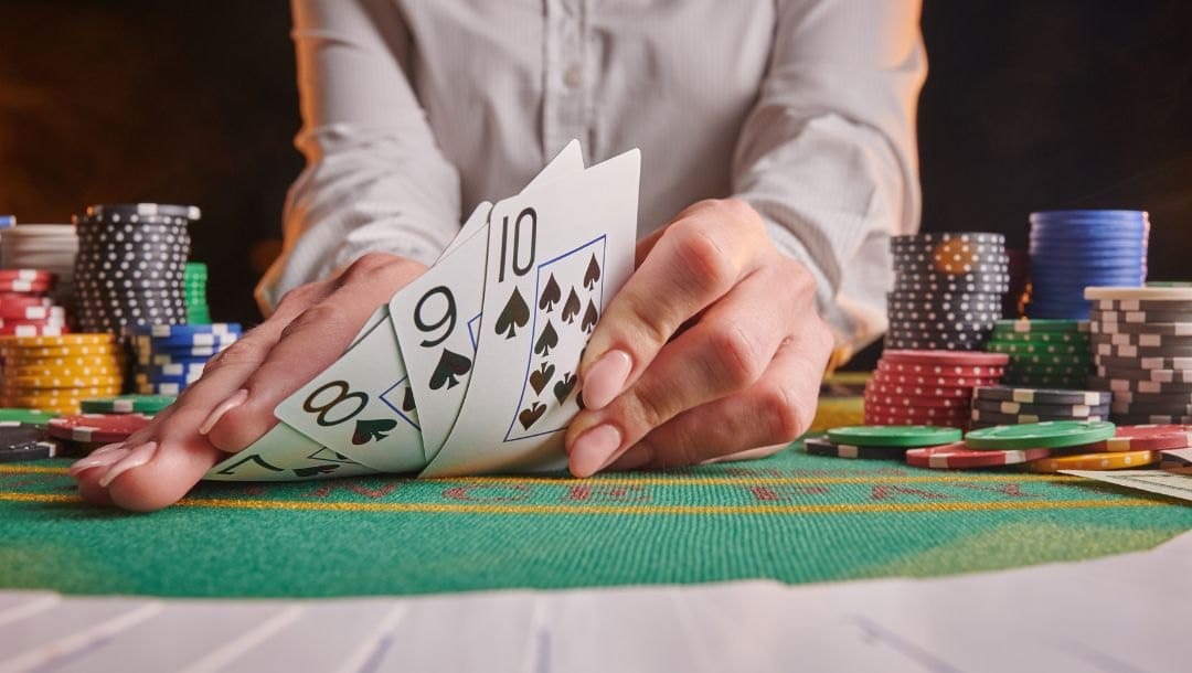 a dealer showing a spade straight of playing cards on a poker table with stacks of poker chips on it