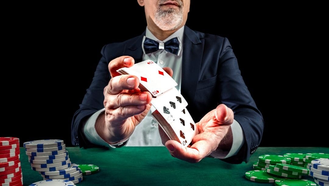 a man wearing a suit and bowtie is shuffling playing cards above a green felt poker table with poker chips on it
