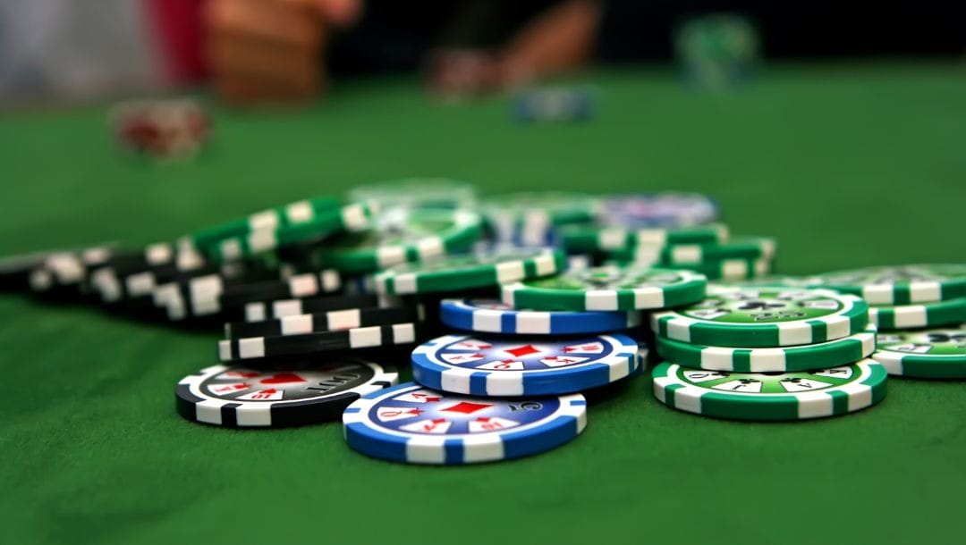 a pile of green, blue and black poker chips on a green felt poker table