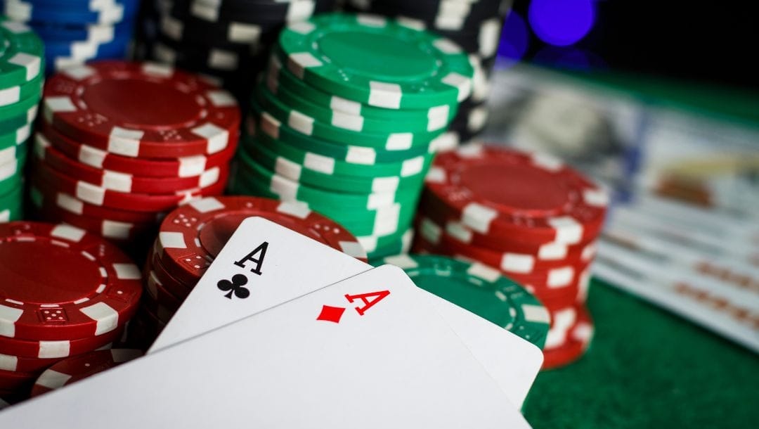 a pair of ace playing cards in front of stacks of poker chips on a green felt poker table