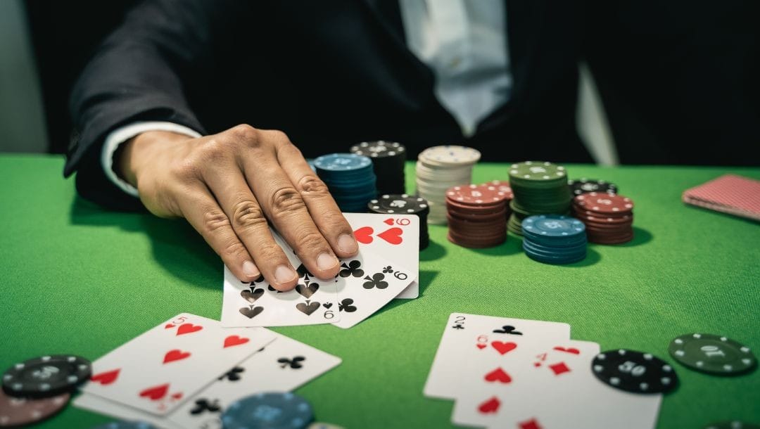 a man shows three of a kind nines on a green felt poker table with other playing cards and poker chips on it