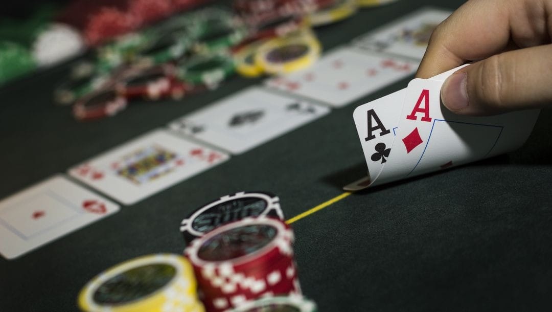 a person showing their ace playing cards on a poker table with poker chips