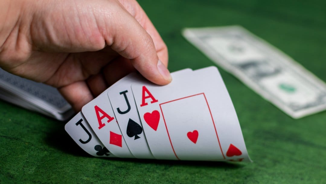 A poker player checks their four hole cards. They have two aces and two jacks.