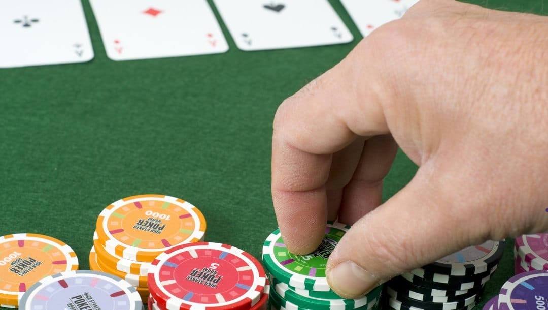 A poker player about to pick up poker chips from their stacks.
