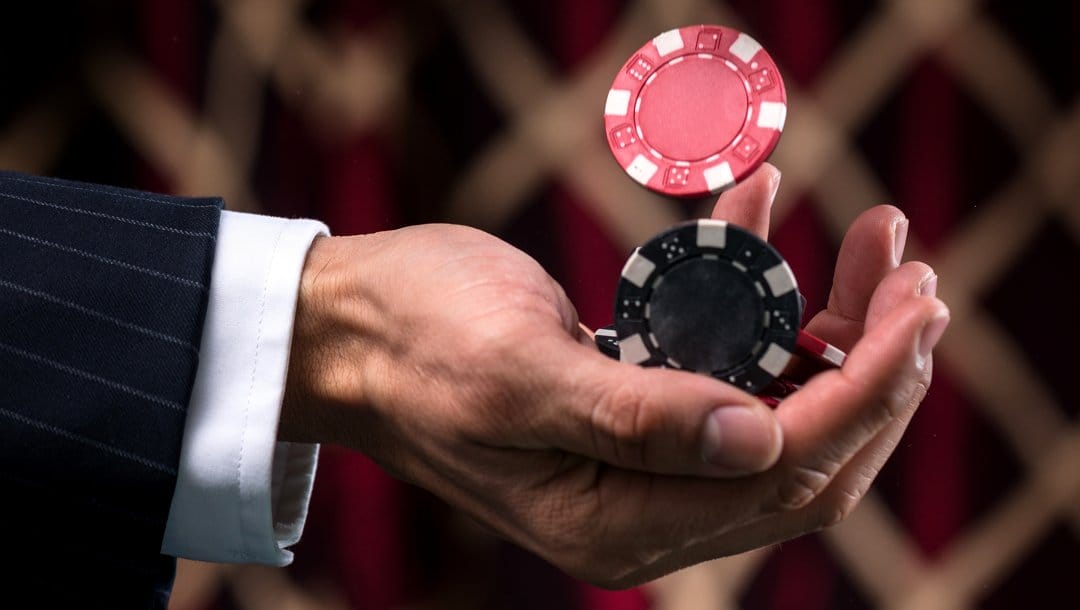 A man catching casino chips in his hand.