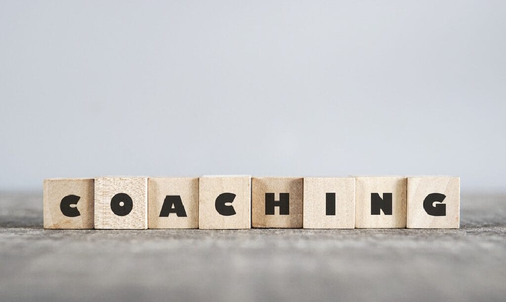 The word “coaching” spelled out on wooded blocks on a table