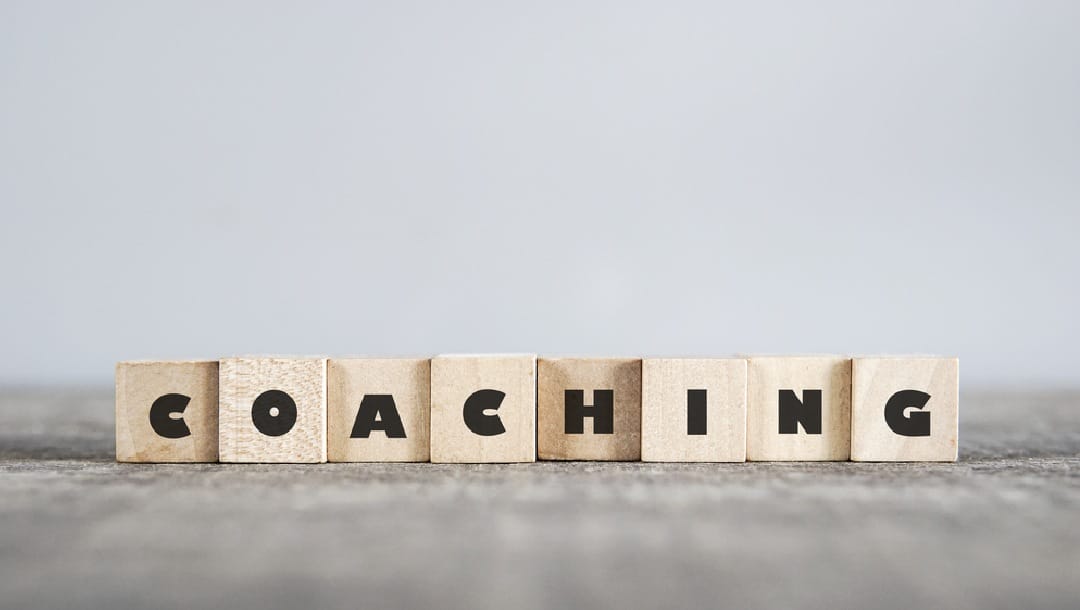 The word “coaching” spelled out on wooded blocks on a table