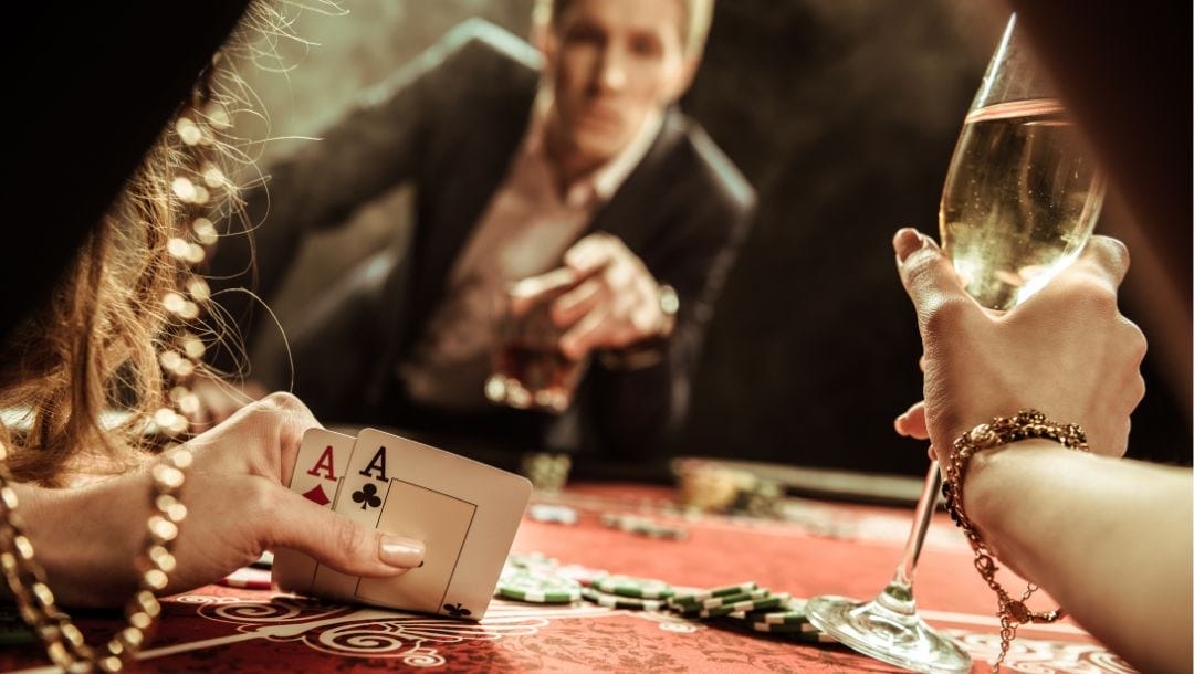 A person engaging in a game of poker, with an Ace of Clubs and an Ace of Diamonds in her hand.