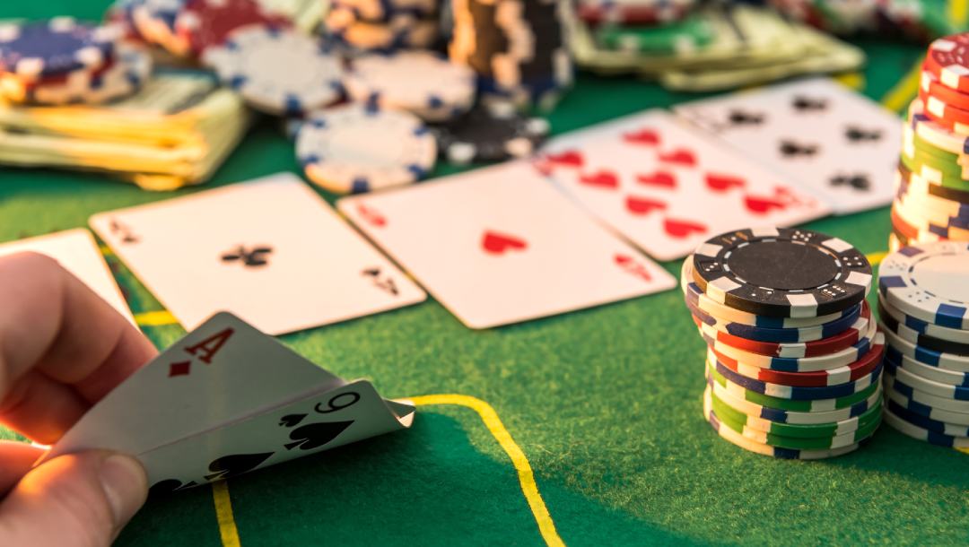 Fingers showing playing cards with casino chips.