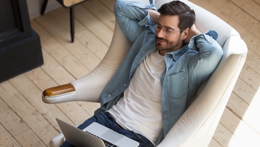 A man smiling with a laptop on his lap.