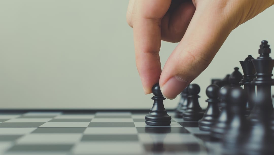 A hand moving a chess piece on the board.