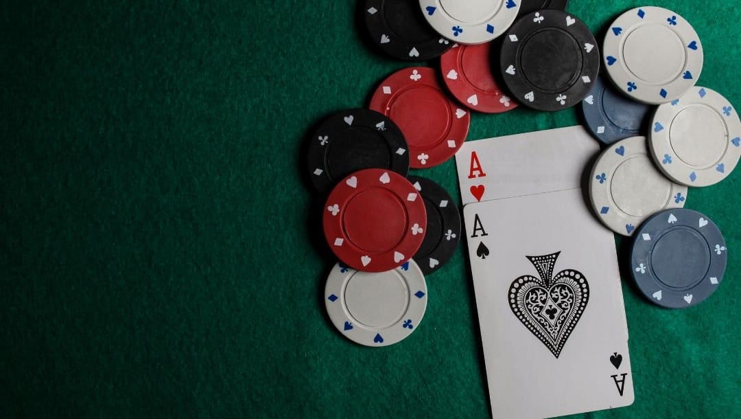 An Ace of Spades, and an Ace of Hearts, on a poker table, surrounded by casino chips.