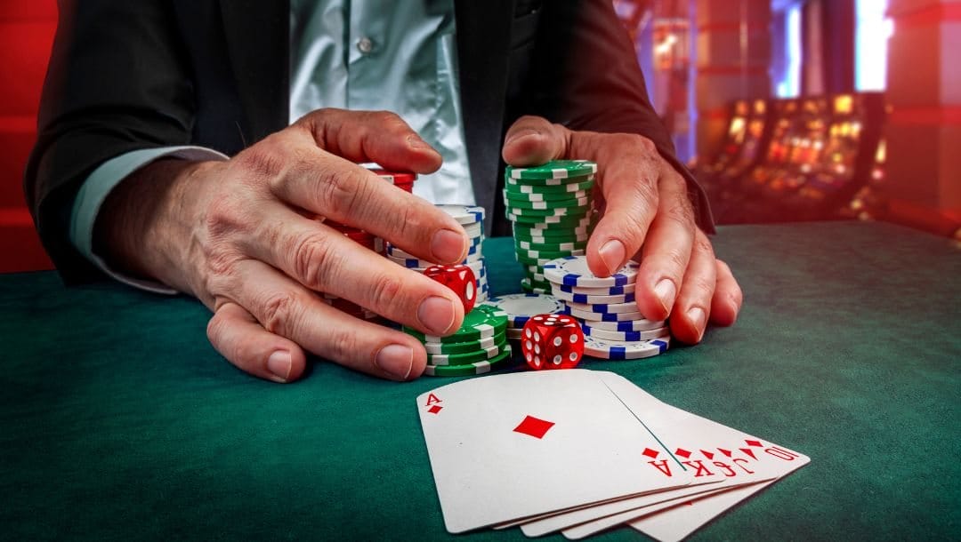 A person's hands collecting casino chips on a poker table, with playing cards neatly arranged in front of him.