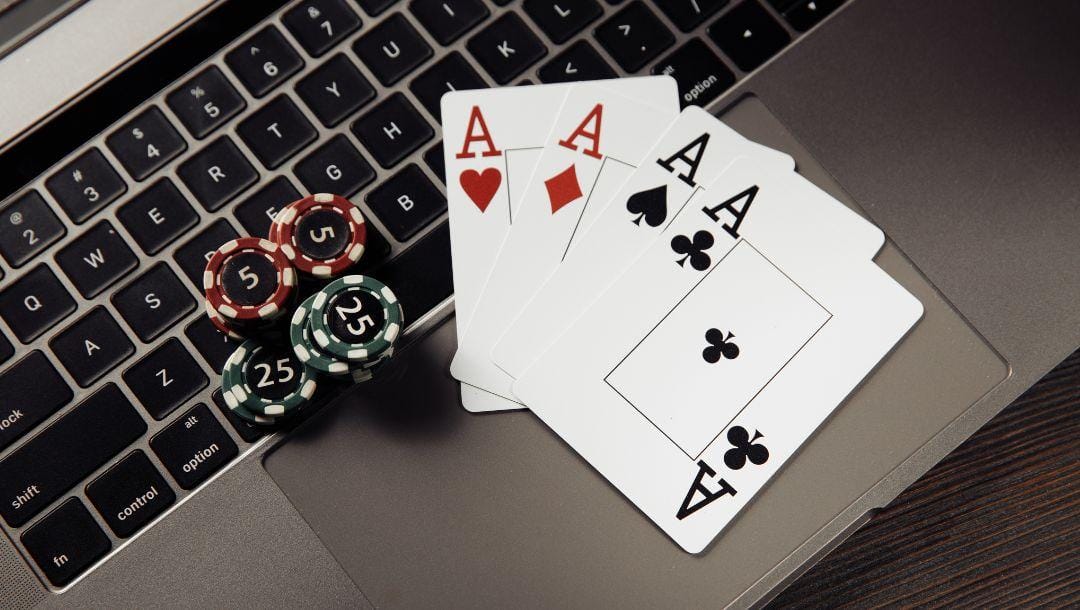 four of a kind ace playing cards and poker chips on a laptop keyboard