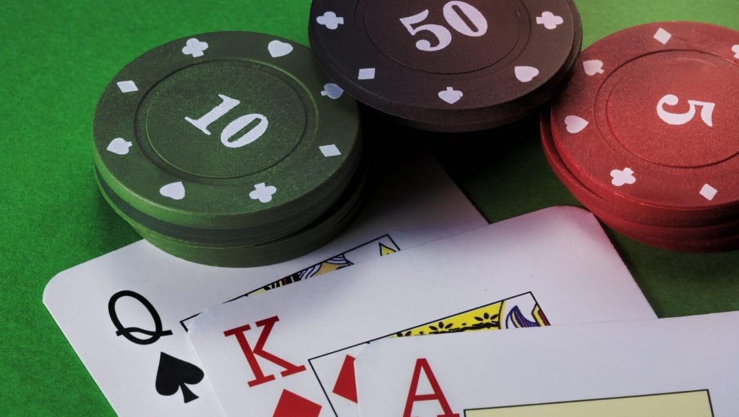 Casino chips and playing cards on a green felt table.
