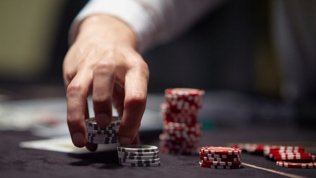 A man playing poker picking up chip stacks.