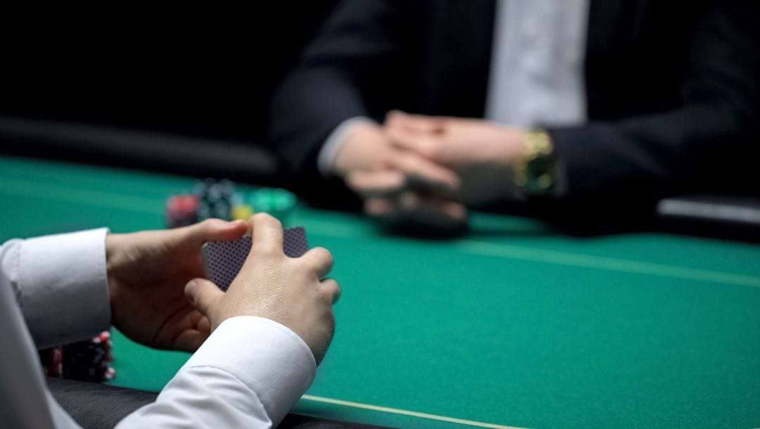 A dealer shuffling cards at a poker table, with a person sitting across from the dealer