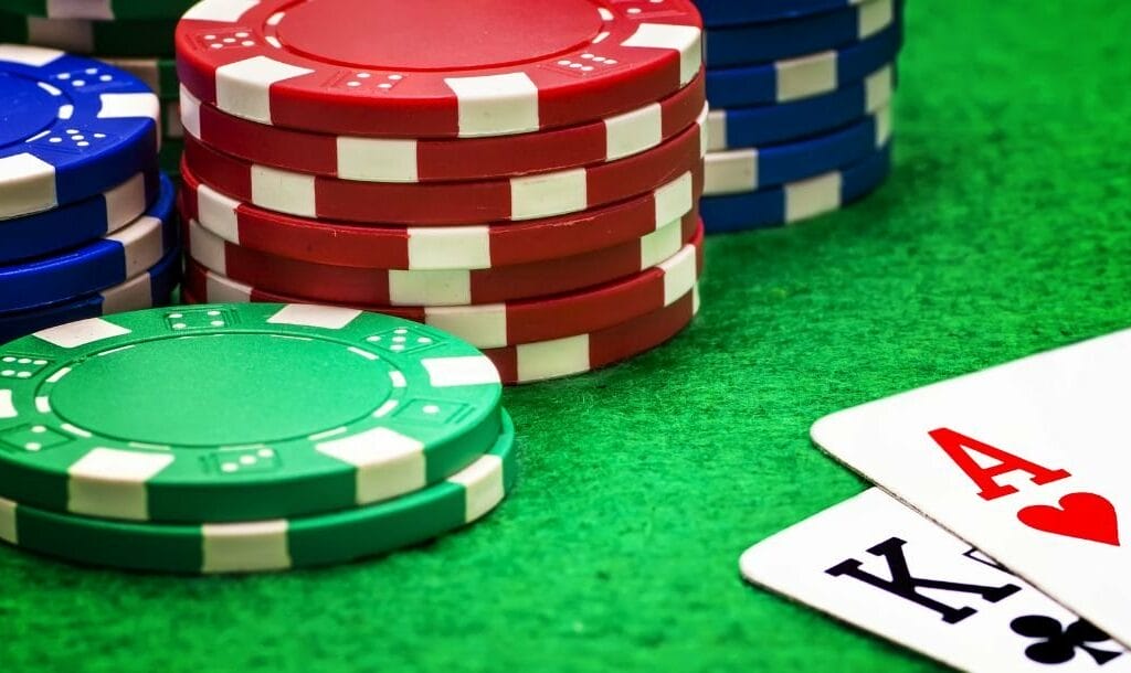 An Ace of Hearts and a King of Clubs, and stacks of casino chips arranged on a poker table.