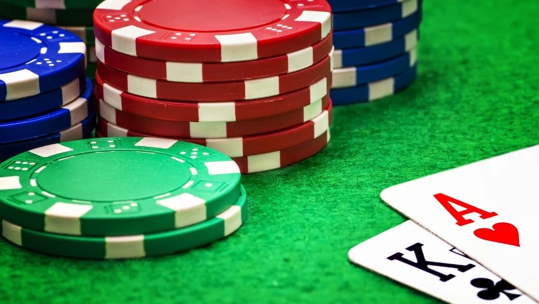 An Ace of Hearts and a King of Clubs, and stacks of casino chips arranged on a poker table.