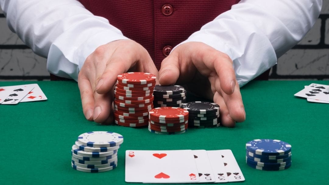 A casino dealer sliding a stack of chips across the poker table, with playing cards strategically arranged.