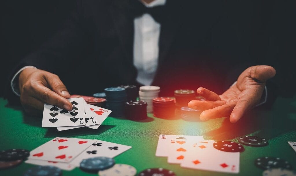 A casino dealer seated at a poker table, dealing cards to players, with casino chips arranged on the table.
