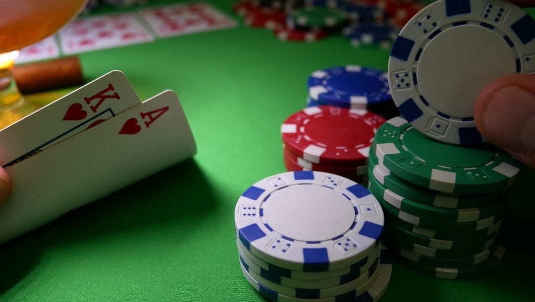A King of Hearts, and an Ace of Hearts being revealed at a poker table, surrounded by neatly stacked casino chips.