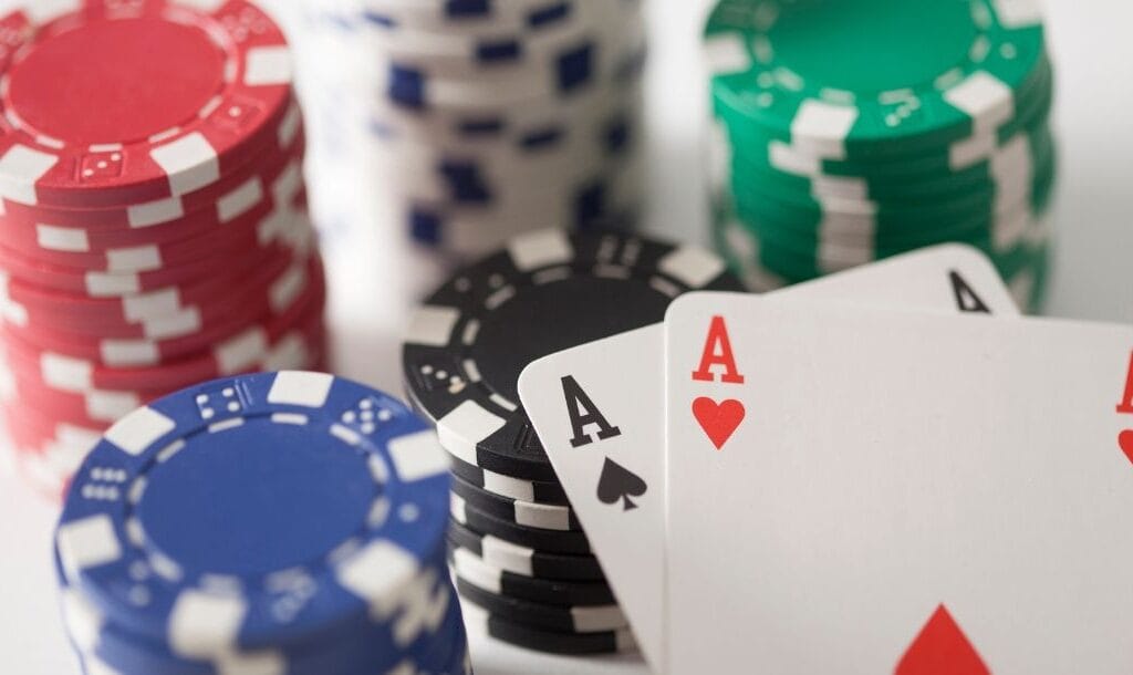 An Ace of Hearts, and an Ace of Spades arranged on top of stacks of casino chips.