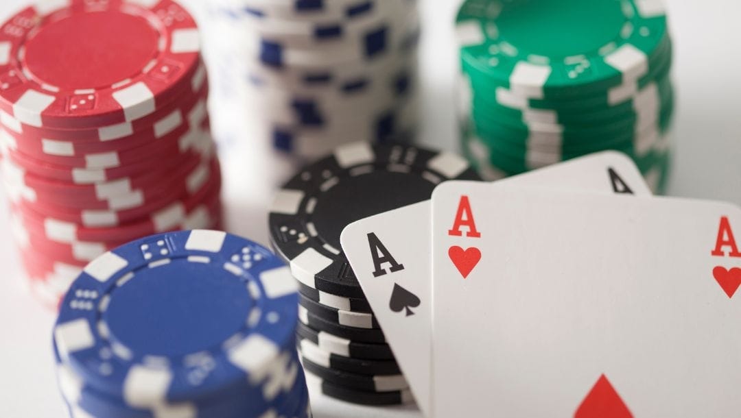 An Ace of Hearts, and an Ace of Spades arranged on top of stacks of casino chips.