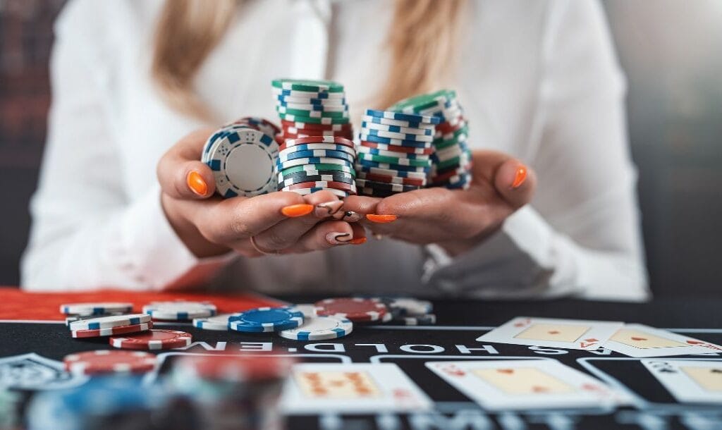 Close-up of a poker player cupping their hands and holding stacks of poker chips.