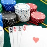 Four aces sitting on a casino table surrounded by stacks of poker chips.