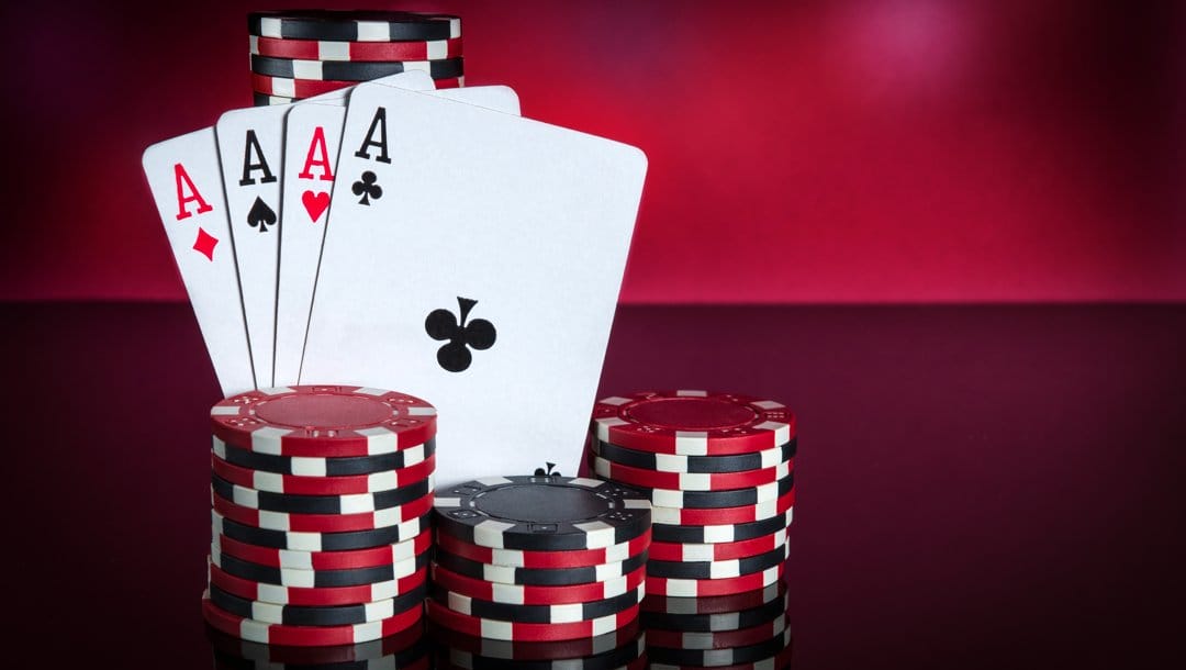 Four aces leaning against stacks of poker chips.