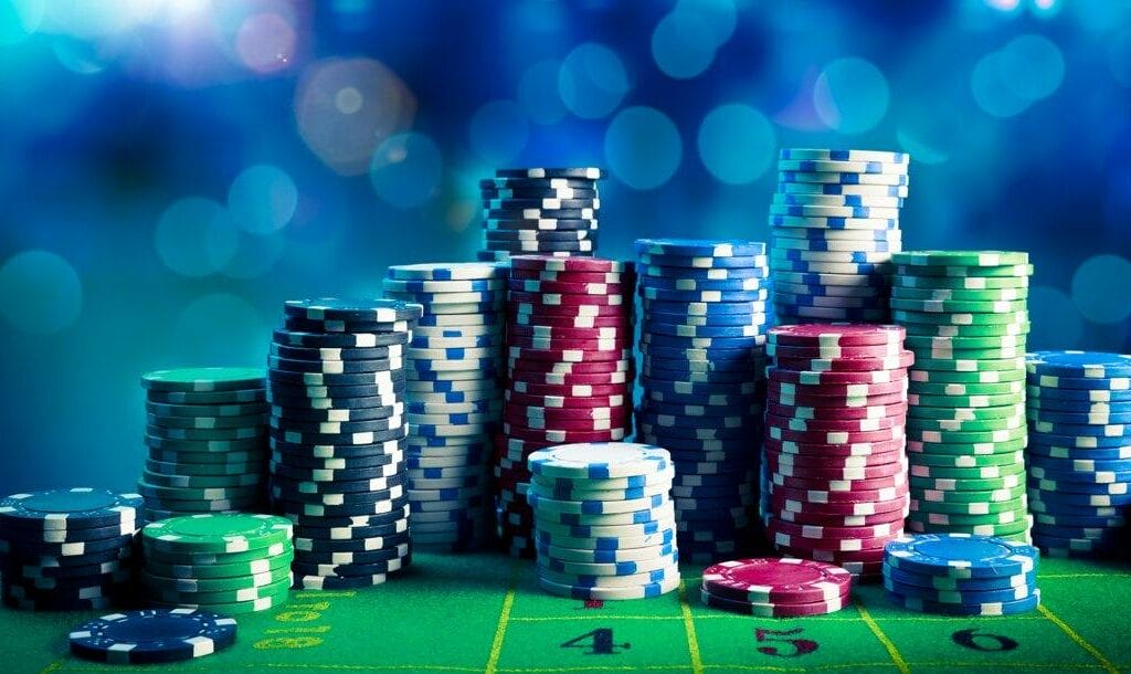 Stacks of white, red, green, blue, and black poker chips on a casino table.