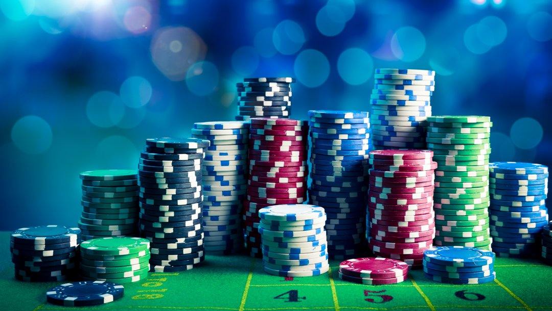 Stacks of white, red, green, blue, and black poker chips on a casino table.