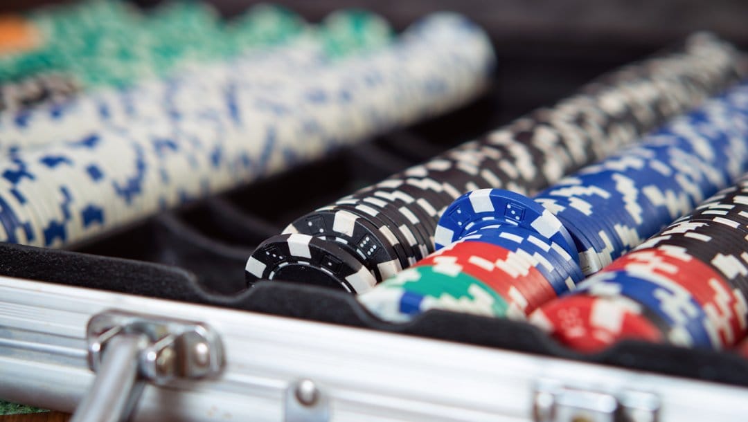 A close-up of a poker set filled with black, green, red, blue, and white poker chips.