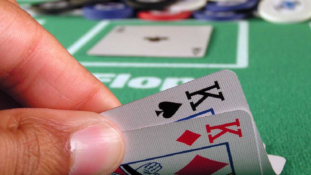 A poker player looks at two kings in a hand.