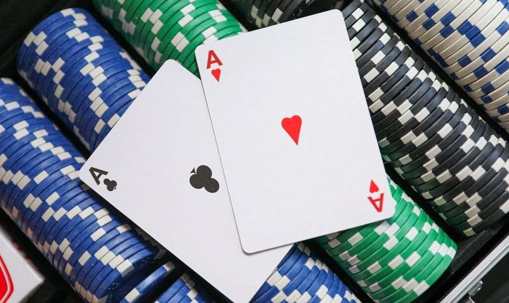 A pair of aces sits on top of stacks of poker chips in a poker-chip case.