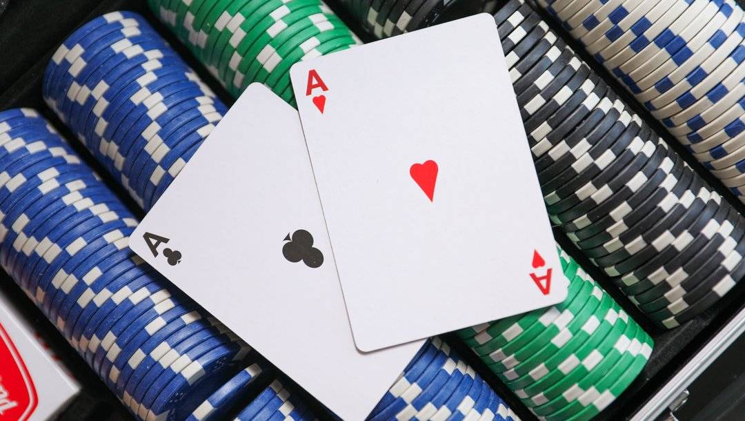 A pair of aces sits on top of stacks of poker chips in a poker-chip case.