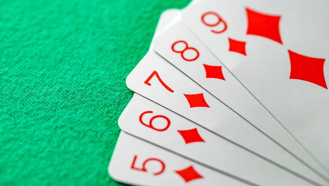 A nine-straight of diamonds sitting on a green felt table.