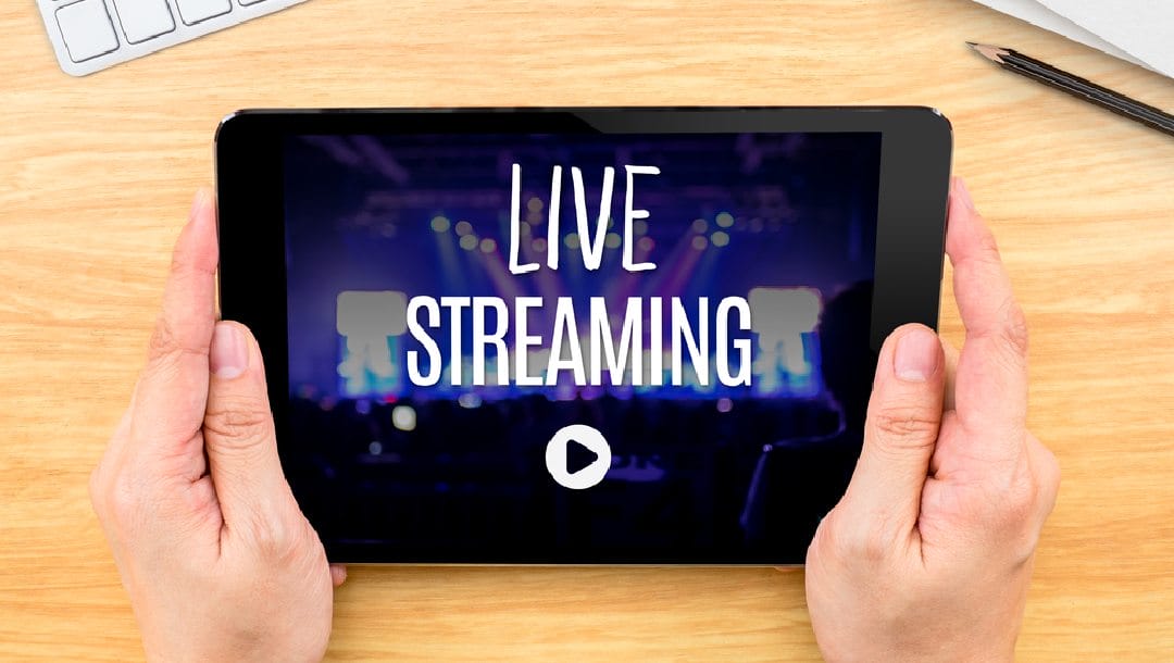 A person live-streaming on a tablet while sitting at a desk.