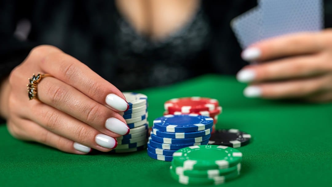 A woman touching casino chips and holding playing cards.