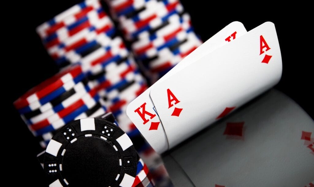 Playing cards with poker chips against a black background.