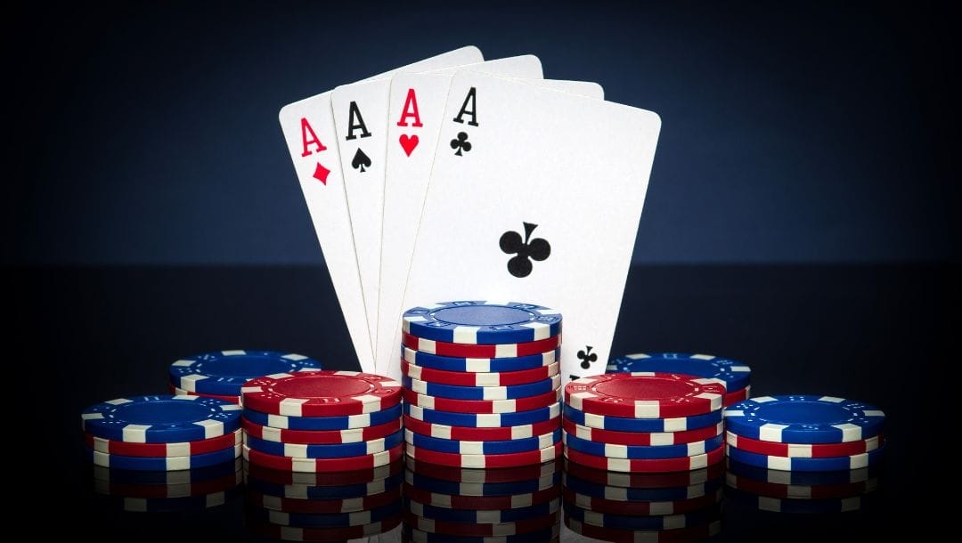 a four of a kind poker hand made up of Ace cards, balancing against short poker chip stacks.