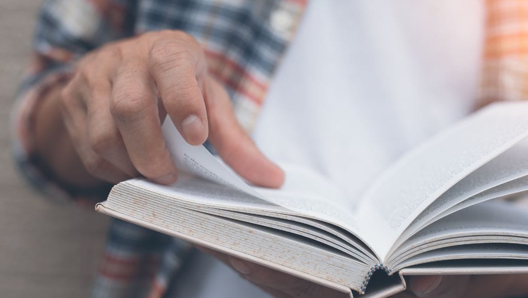 Hand holding a book, delicately turning a page