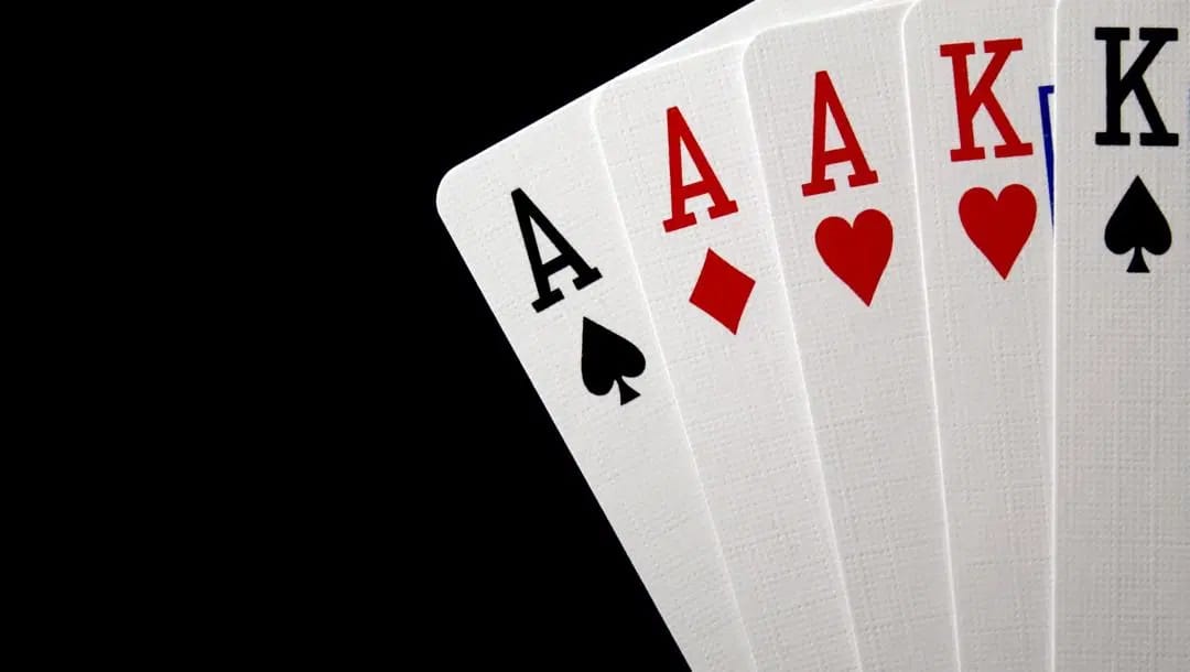 Five playing cards in the righthand corner against a black background.