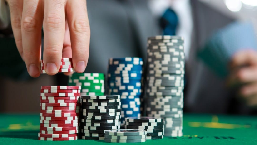 Hand picking chips from piles of poker chips of varying colors