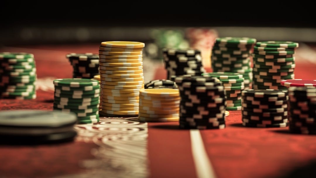 Green, yellow, and black poker chips stacked on a red table