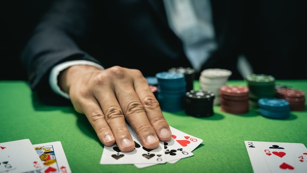 A man lays out a hand of three nines on a poker table