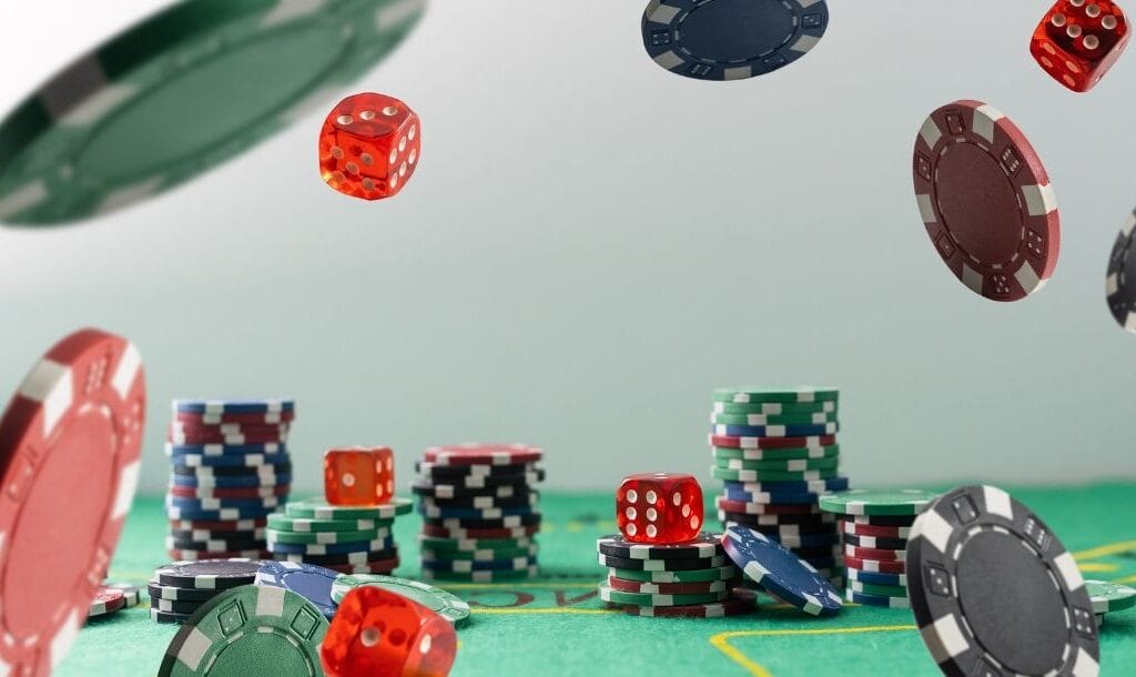 stacks of poker chips and red six-sided dice on a green felt poker table with poker chips and red six-sided dice falling in front of them